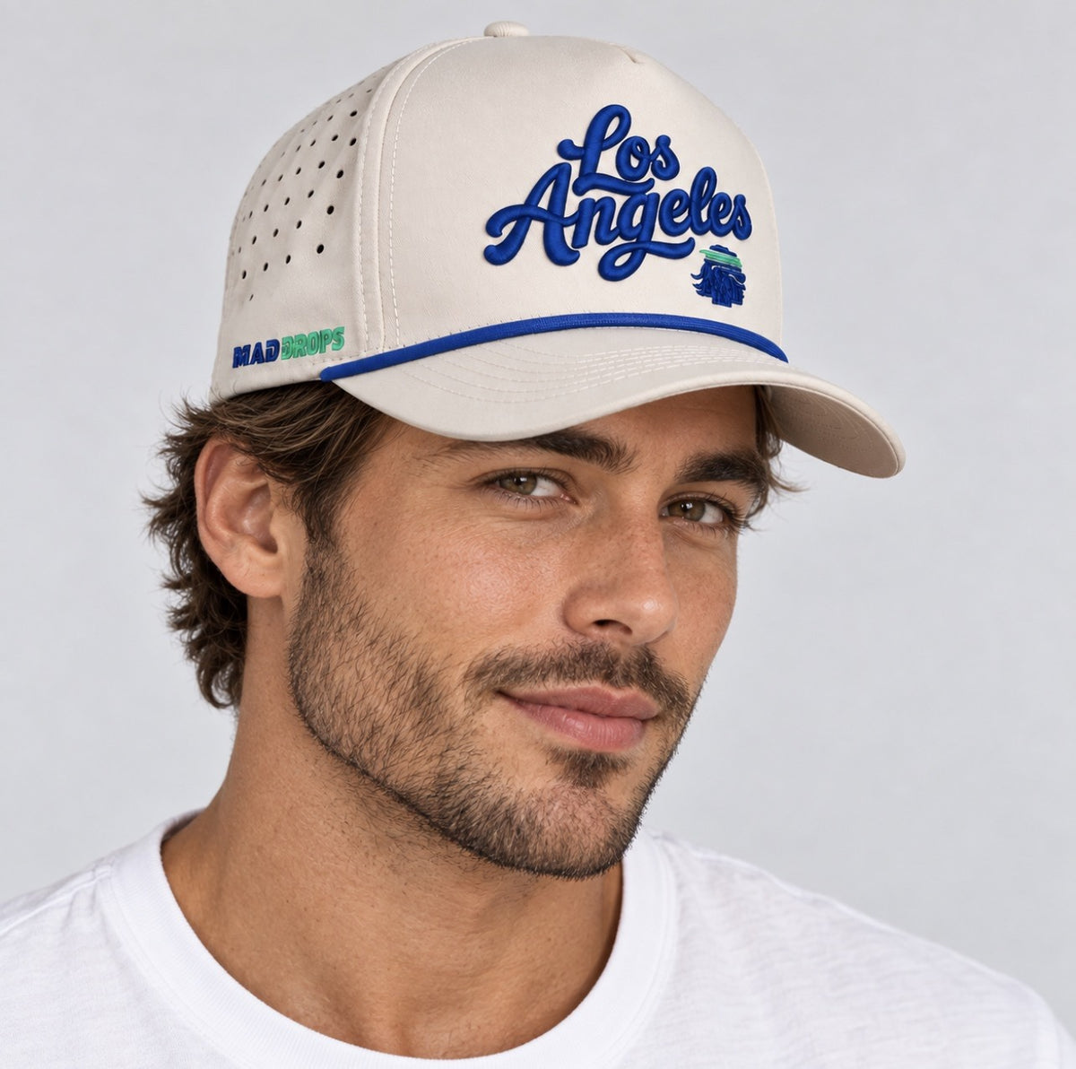 West Coast Cap in bone with raised royal blue Los Angeles script, worn by a model